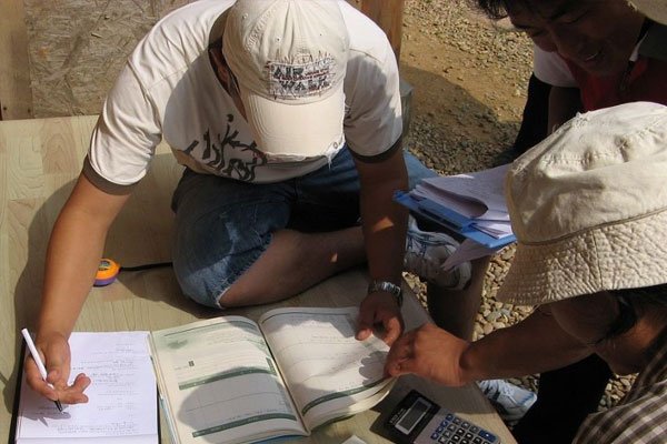 Estudiantes sentados en las zonas verdes del campus universitario conversando.