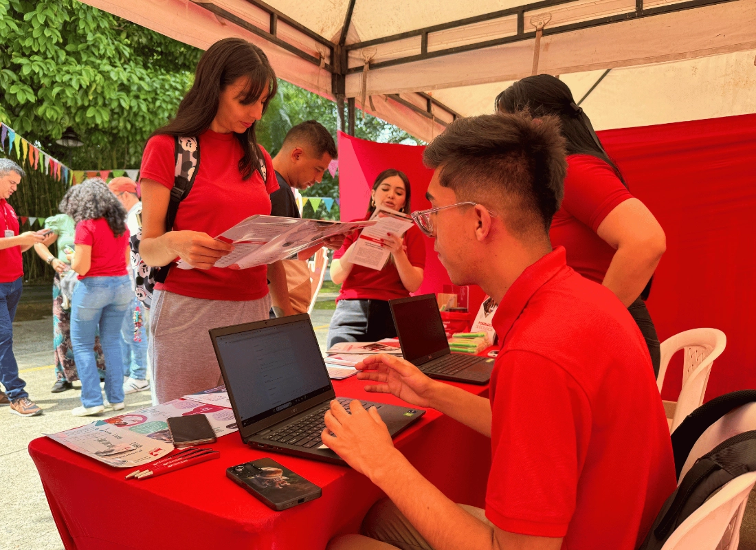 Asesores brindando información personalizada a estudiantes con apoyo de equipos portátiles.