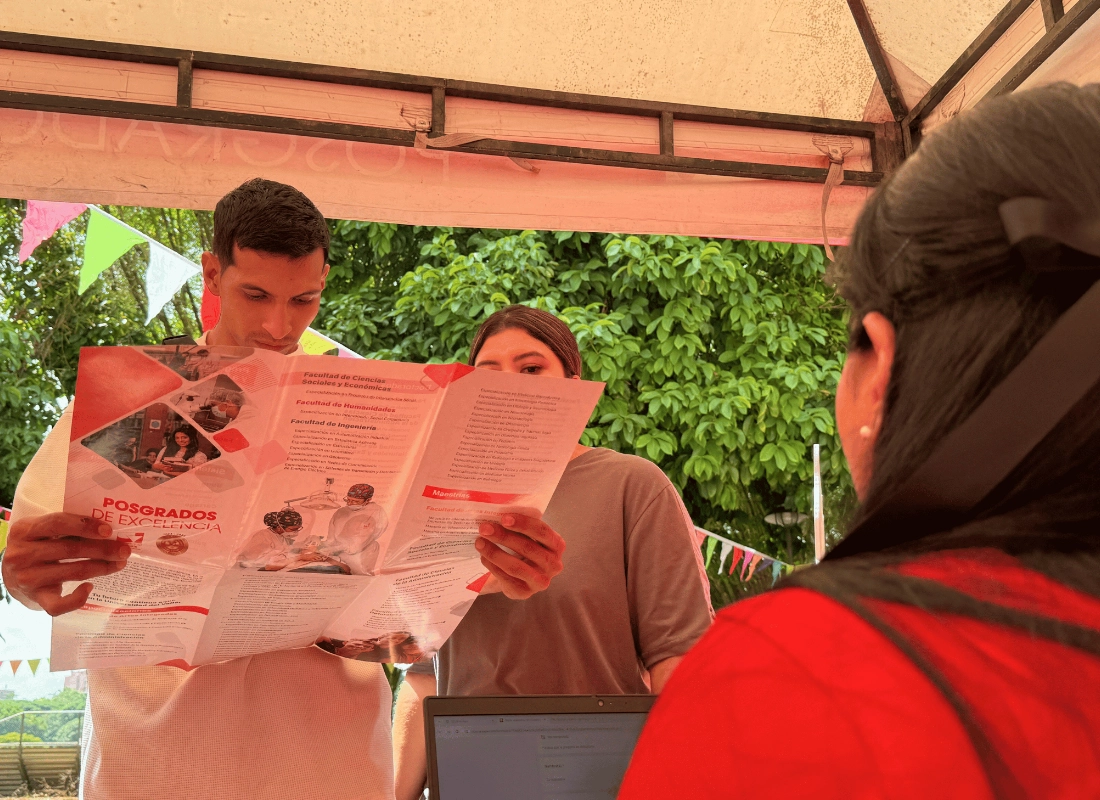 Estudiantes consultando folletos sobre la oferta académica de posgrados.