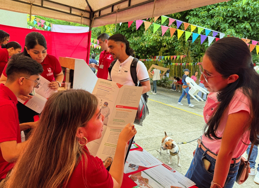 Interacción de visitantes con el equipo de admisiones en el punto de información.