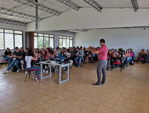 Docente impartiendo clase a un grupo de estudiantes en salón de clase