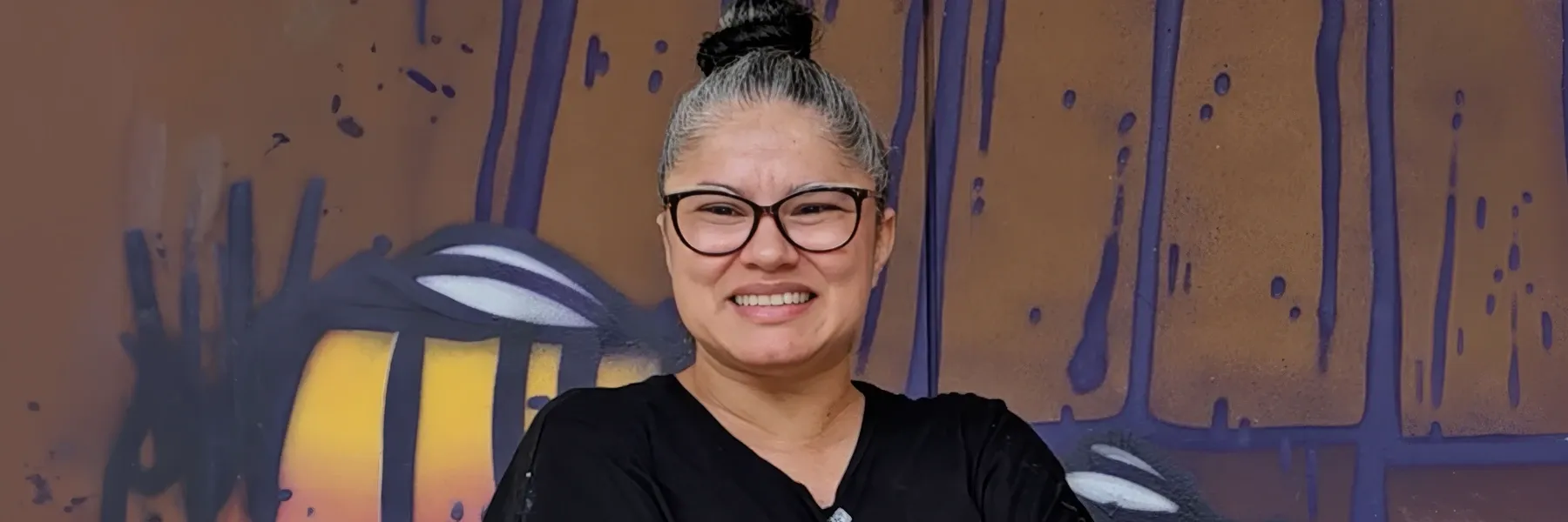 Retrato de Marleyda Soto sonriente con gafas sobre fondo ilustrado